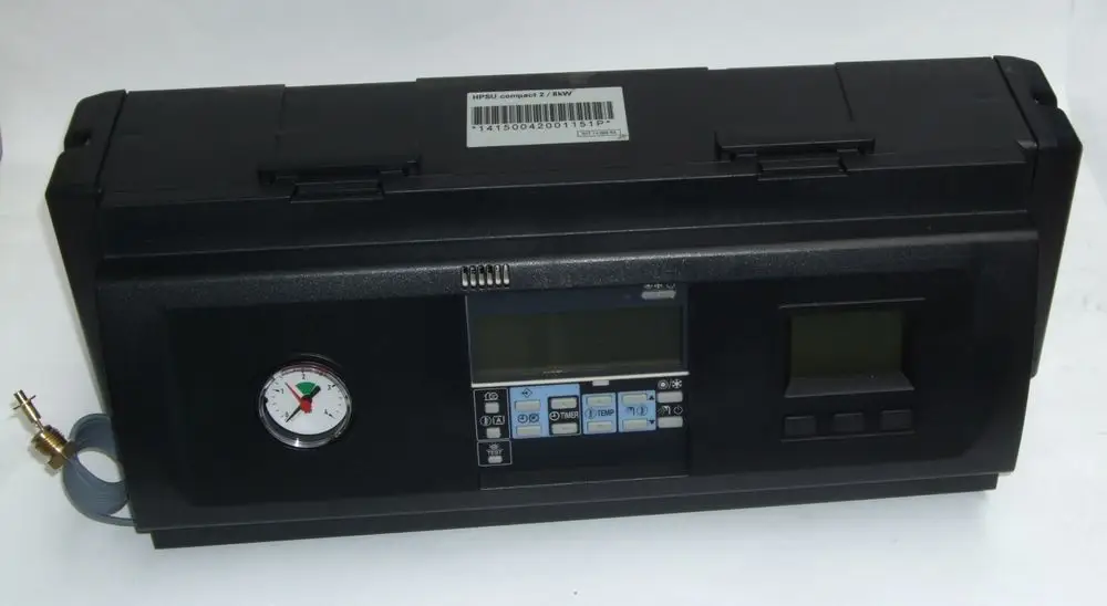 Schwarze Steuereinheit von Daikin mit analogen und digitalen Anzeigen, Druckmesser und Bedientasten auf der Vorderseite. Ein Anschluss mit Schlauch ist seitlich sichtbar.